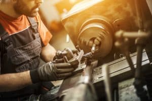 Someone using a lathe at a Calgary machine shop for metal work.