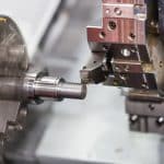 Operator machining automotive part by cnc turning machine